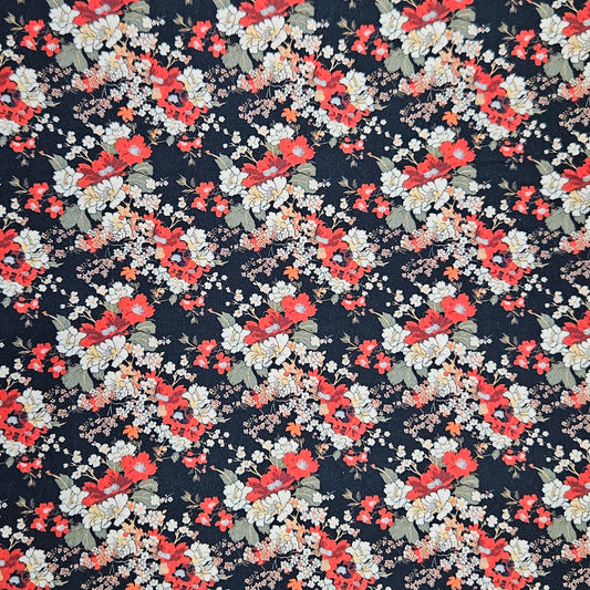 A close-up of a floral fabric pattern featuring red and white flowers with green leaves on a dark navy blue background.