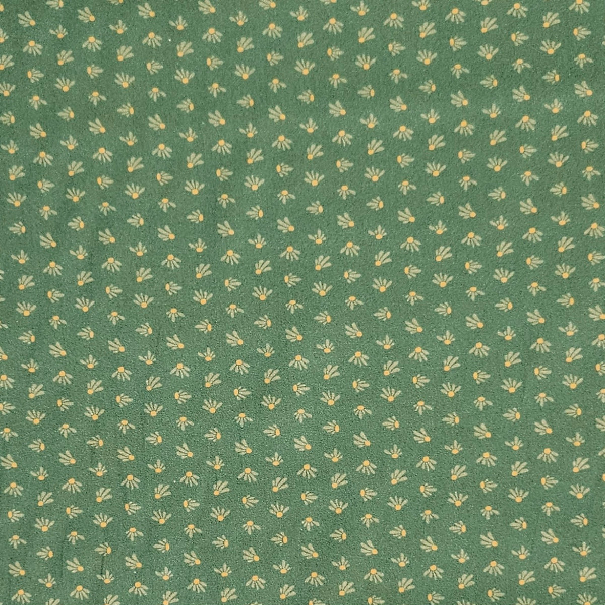 A close-up of a green fabric or wallpaper pattern featuring a repeating small floral motif in pale yellow and off-white.