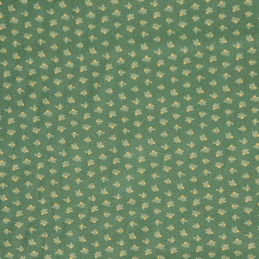 A close-up of a green fabric or wallpaper pattern featuring a repeating small floral motif in pale yellow and off-white.