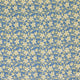 A close-up of a fabric or wallpaper pattern featuring a dense, repeating print of small yellow flowers and green stems on a medium blue background.