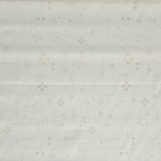 A close-up of a light cream or off-white fabric with a subtle, repeating geometric pattern of small crosses, diamonds, and dashed lines.