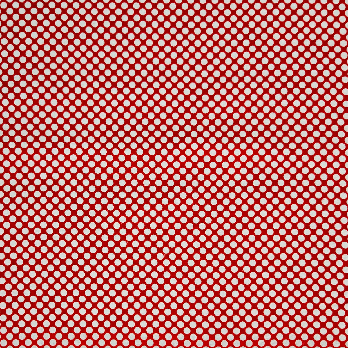 A close-up of a red and white patterned fabric featuring a repeating diagonal grid of small white circles on a red background.
