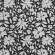 A close-up of a black fabric or wallpaper featuring a repeating white floral and leaf pattern.