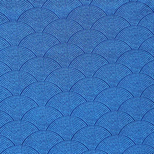 A close-up of a blue fabric or material swatch with a repeating scallop or fan pattern made of small dark dots and lines.