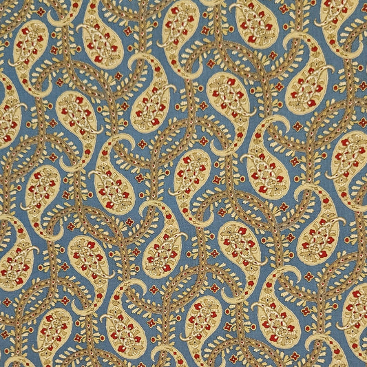 A close-up of a fabric or wallpaper pattern featuring beige and gold paisley motifs with small red floral accents on a muted blue background.