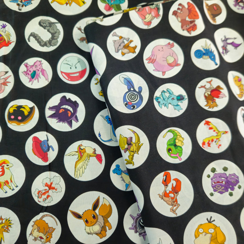 A close-up of a black fabric featuring a repeating pattern of circular white stickers with various colorful cartoon Pokémon characters.