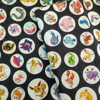 A close-up of a black fabric featuring a repeating pattern of circular white stickers with various colorful cartoon Pokémon characters.