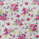 A close-up of a floral fabric pattern featuring pink and magenta roses, yellow blossoms, and green leaves on a light cream background.