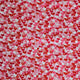 A close-up of a fabric or material swatch featuring a dense pattern of red, pink, and orange hearts on a white background.