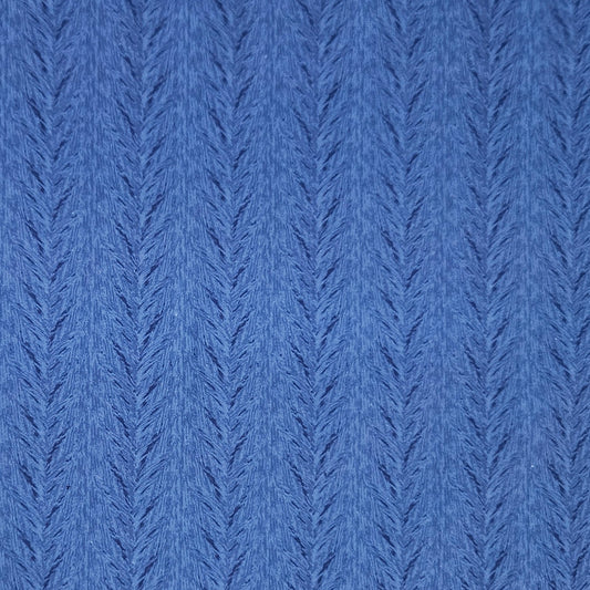 A close-up of a blue textured knit fabric with a repeating chevron or herringbone pattern.